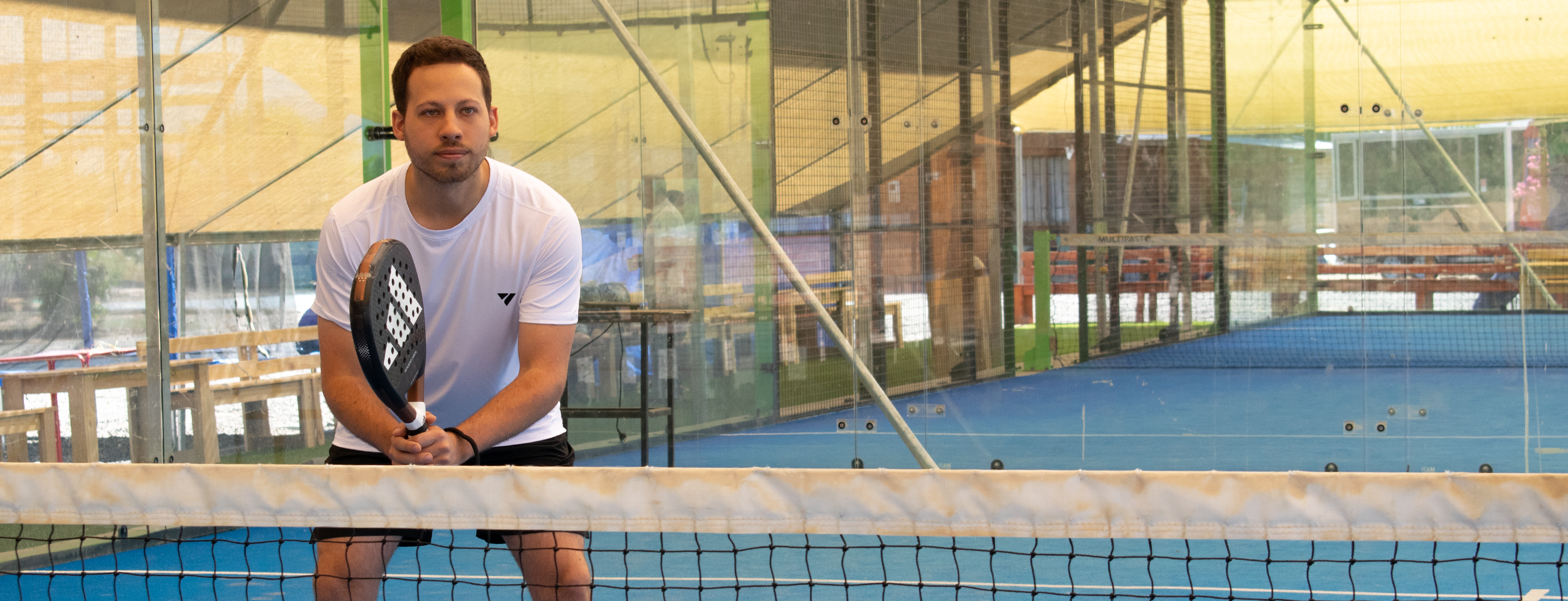 hombre jugando padel sosteniendo pala dentro de la cancha cerca de la red