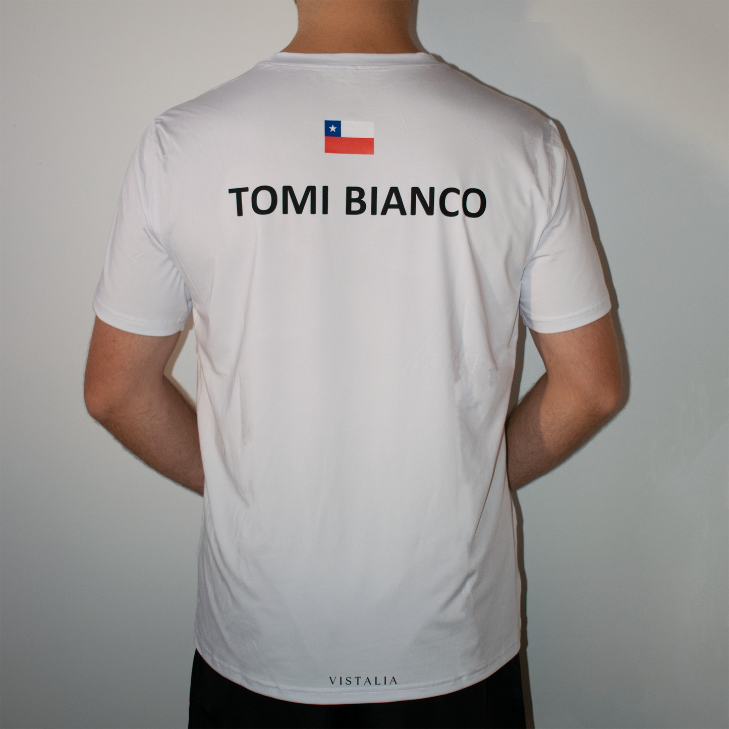 modelo usando polera estampada blanca de espaldas con fondo blanco